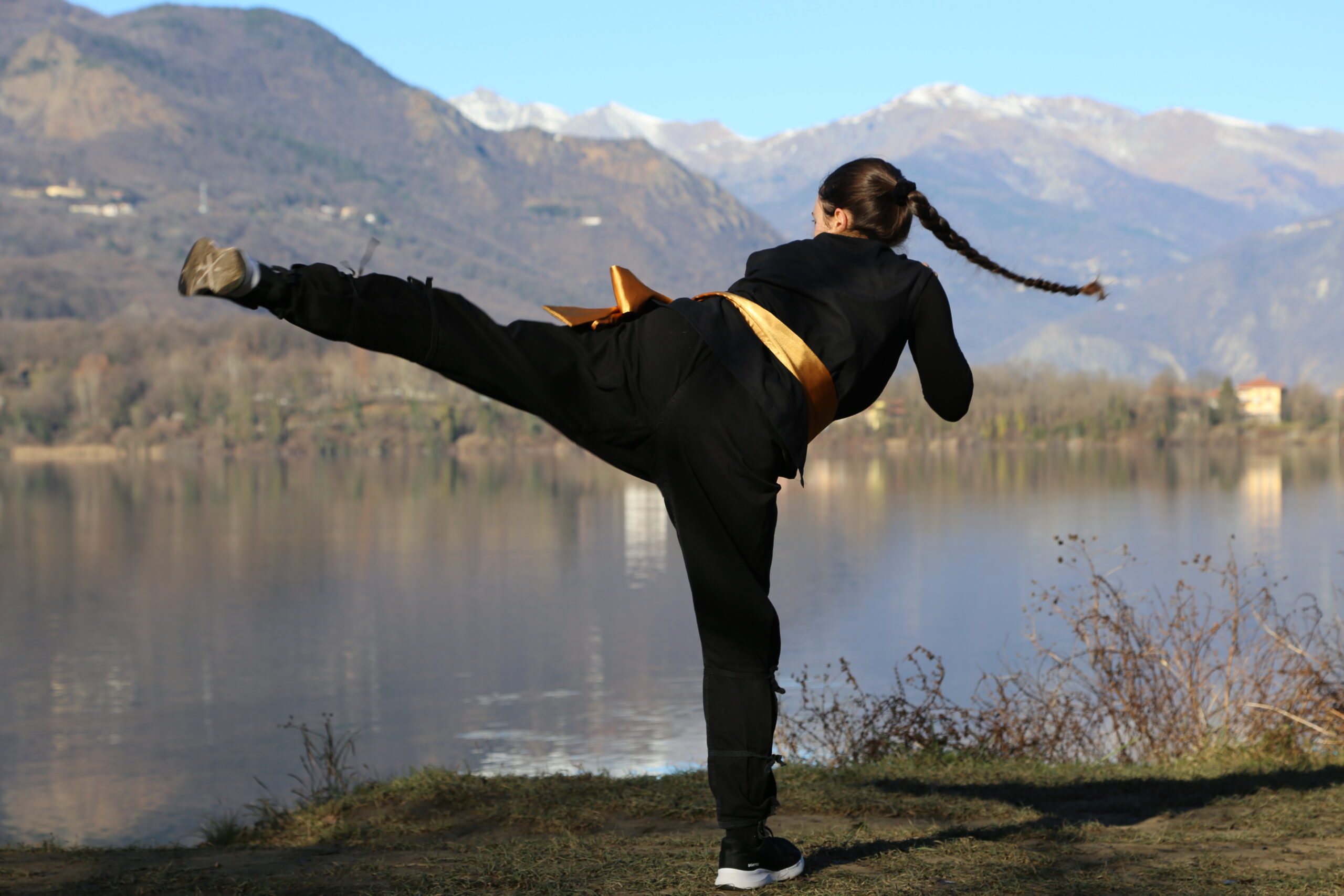 Persona che pratica un calcio alto in un paesaggio montano